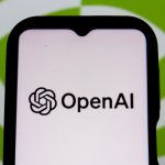 Ilustrasi logo OpenAI di layar ponsel dan komputer
