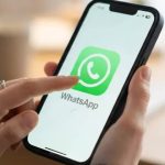 Ilustrasi tangan membuka aplikasi WhatsApp di ponsel