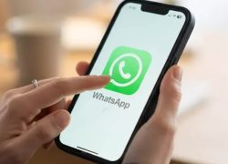 Ilustrasi tangan membuka aplikasi WhatsApp di ponsel