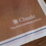 Ilustrasi logo Claude dari Anthropic pada lembar cetak berwarna cokelat